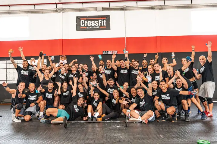 Grupo con los brazos en alto frente al rótulo de CrossFit