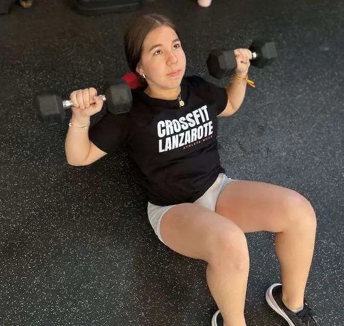 Adolescente entrenando con mancuernas en clase de Teens